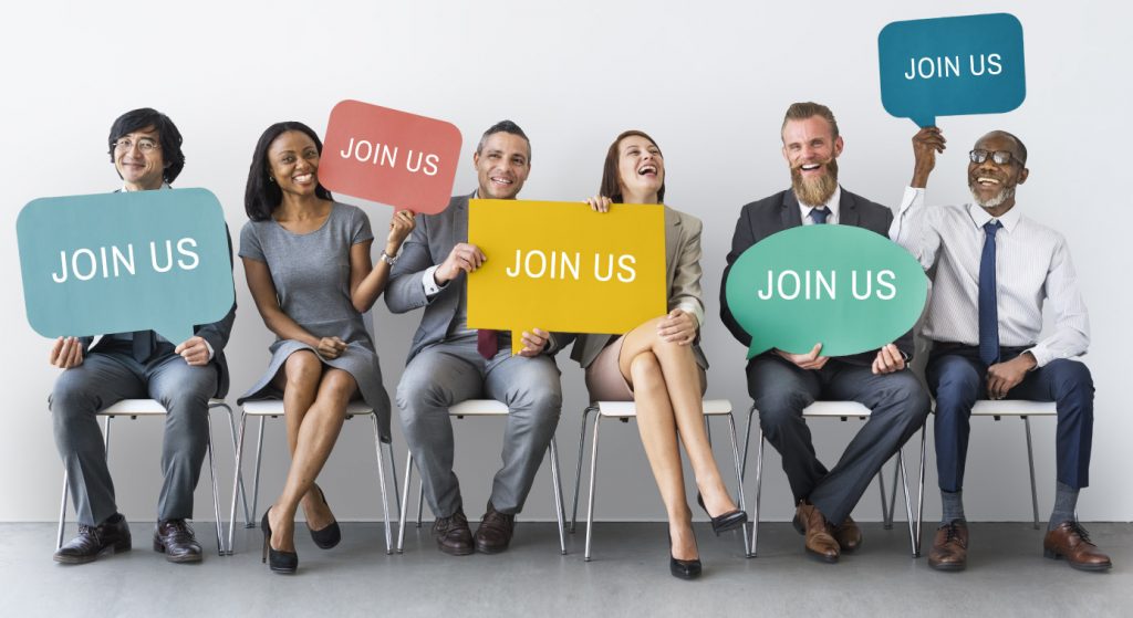 6 people holding signs "join us", careers page